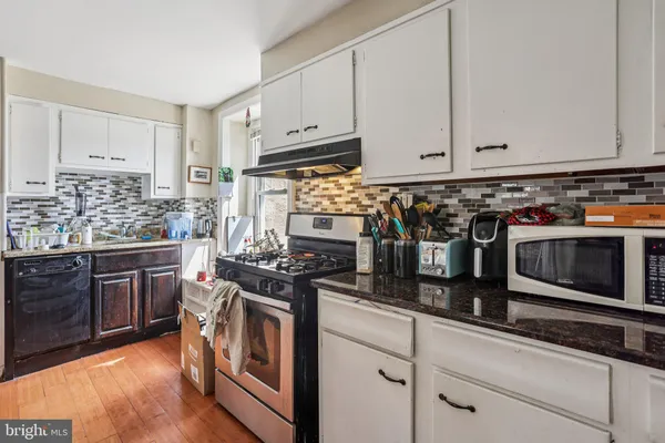 a kitchen with stainless steel appliances granite countertop a stove a sink and a microwave
