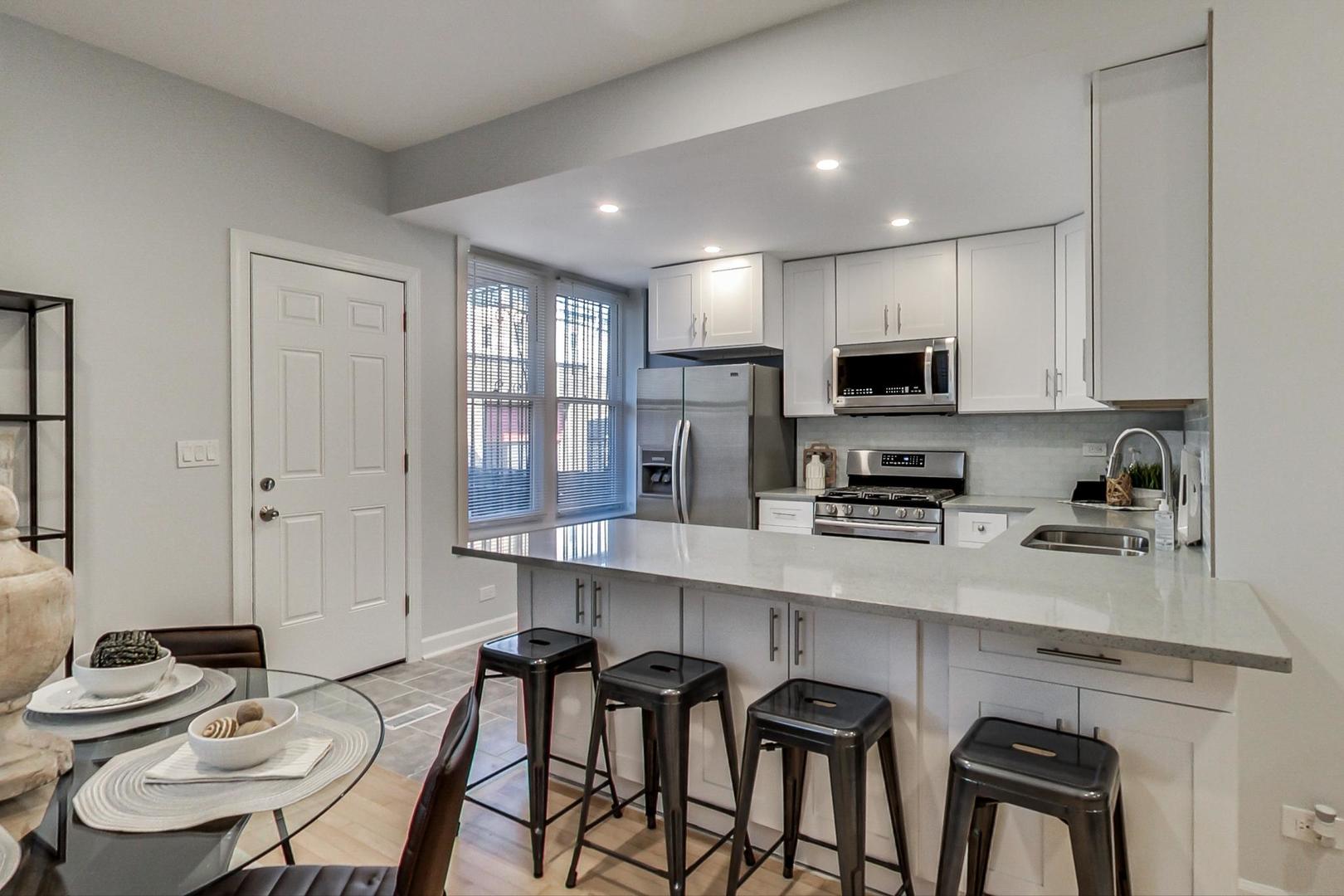 1422 West Lexington Street, Unit 2F Chicago, IL 60607 - Photo 8 of 19 a kitchen with stainless steel appliances granite countertop a stove top oven a sink a stove a dining table and chairs