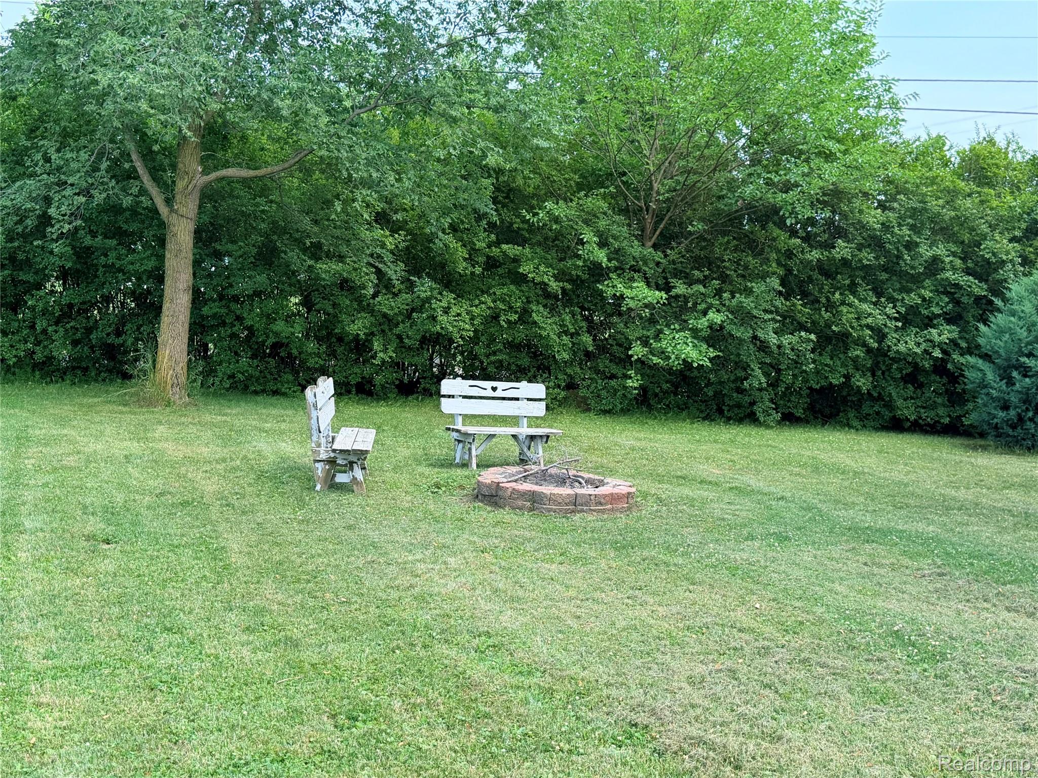 3840 East Dunbar Road Monroe, MI 48161 - Photo 35 of 38 Expansive lawn area featuring a brick-ringed fire pit and mature perimeter landscaping