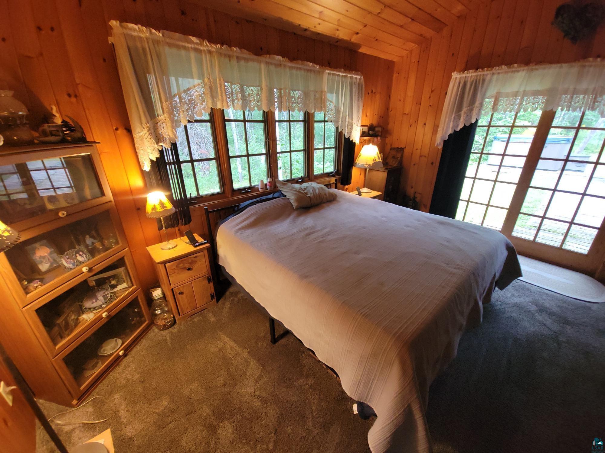 181 Linnell Road Grand Marais, MN 55604 - Photo 46 of 77 Wood paneling throughout, built-in wooden display cabinet, wood-finish flooring, multiple windows, and a sliding glass door