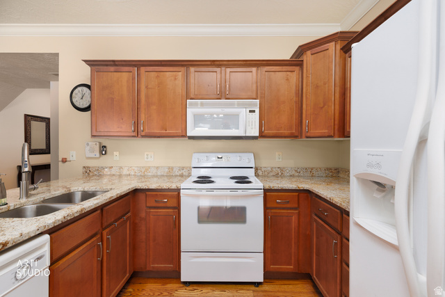 6761 950 East Midvale, UT 84047 - Photo 13 of 44 Kitchen featuring wood cabinetry, light-toned countertops, a double basin sink with a high-arc faucet, white appliances, and wood-finish flooring