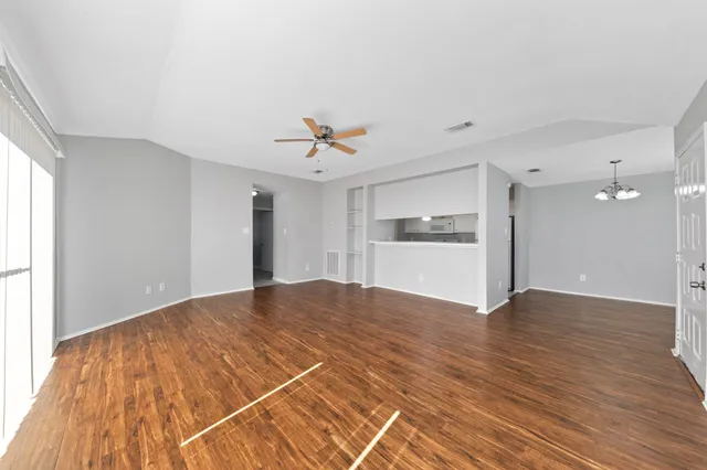 a view of empty room with wooden floor and window