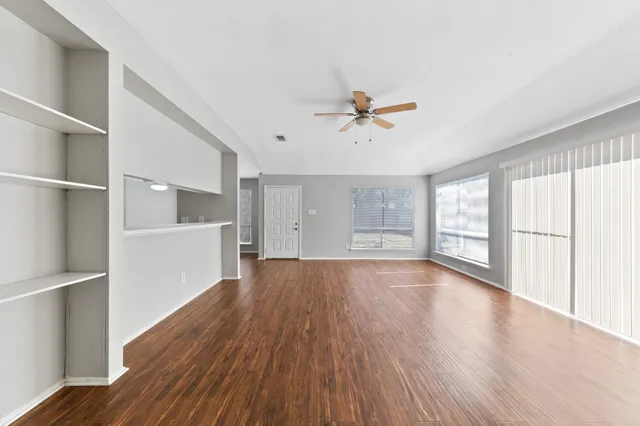 a view of an empty room with a window and wooden floor