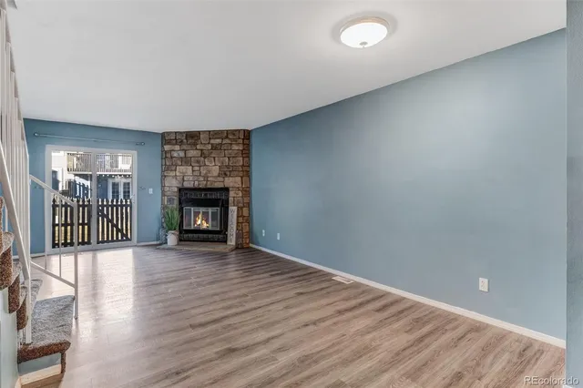 an empty room with wooden floor fireplace and windows