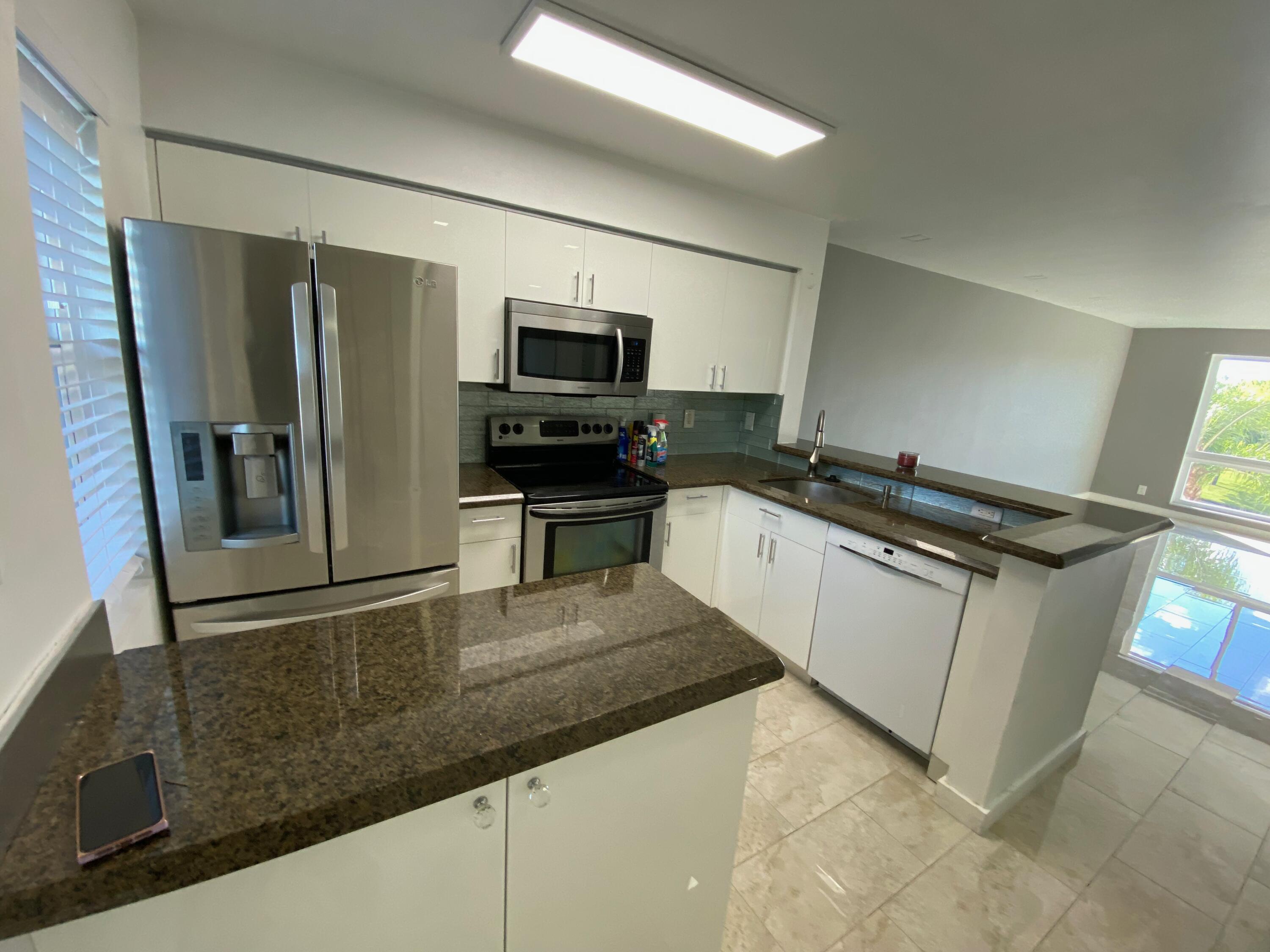 2108 South Cypress Bend Drive, Unit 406 Pompano Beach, FL 33069 - Photo 1 of 12 a kitchen with granite countertop a refrigerator and a stove top oven