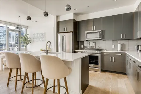 a kitchen with stainless steel appliances kitchen island granite countertop a sink a stove a refrigerator cabinets and chairs