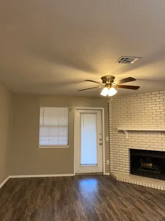 a view of a livingroom with a fireplace a ceiling fan and wooden floor