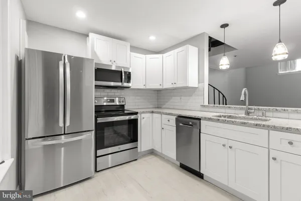 a kitchen with stainless steel appliances white cabinets and a refrigerator