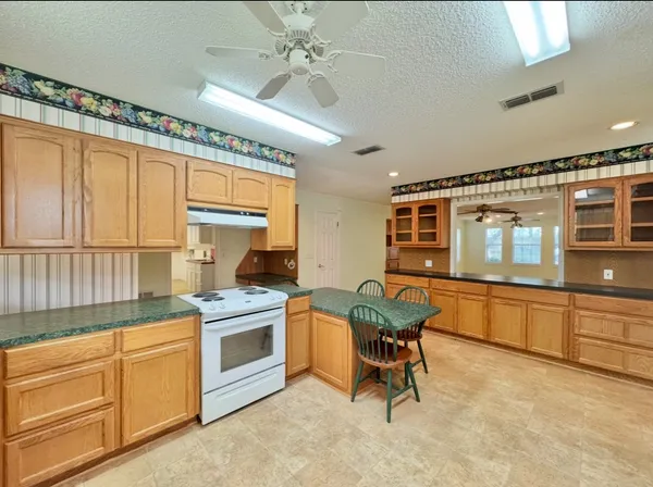 a view of a livingroom with a ceiling fan window and a kitchen view