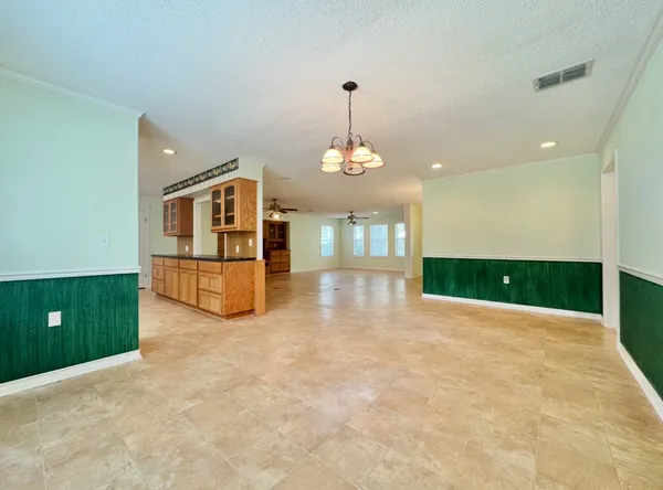 a view of an empty room with a window and kitchen view