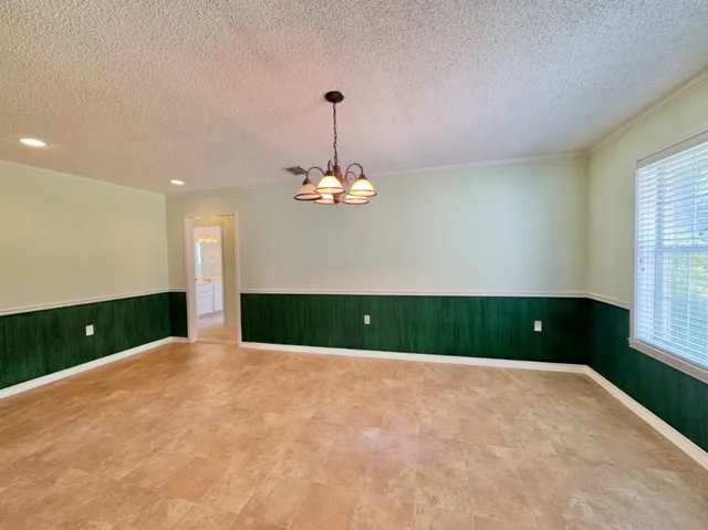 a view of an empty room with a window and kitchen view