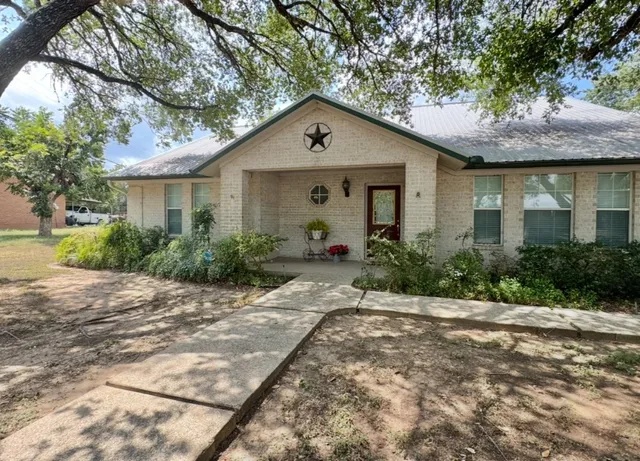 a front view of house with yard and trees around