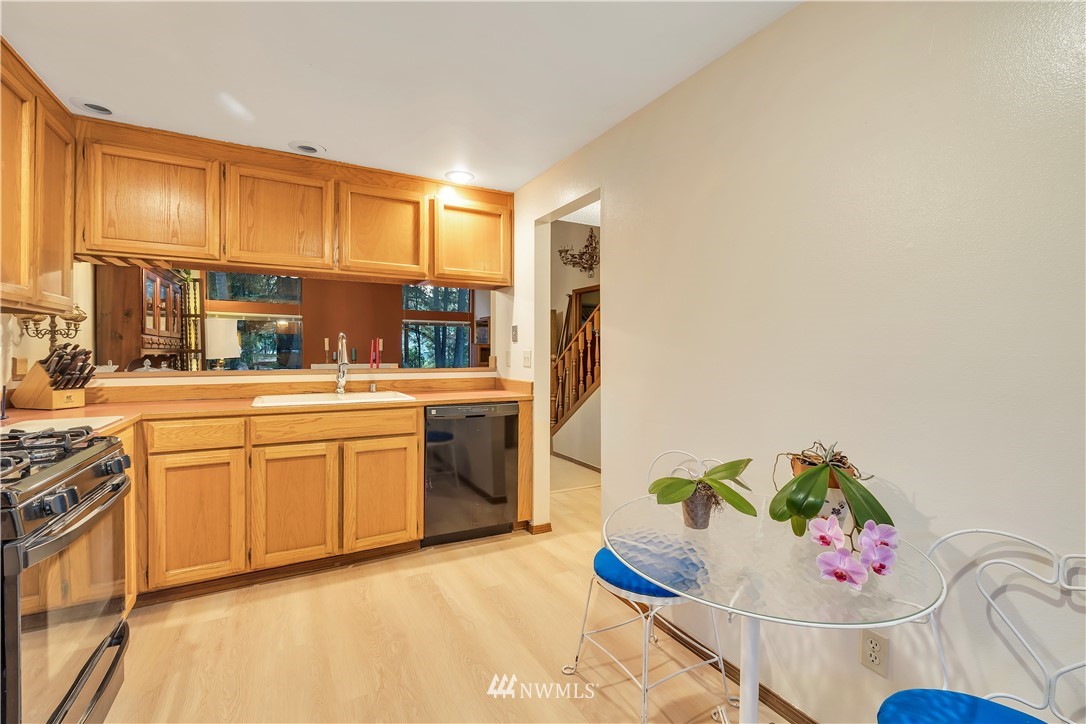 25419 213th Place Southeast, Unit 60 Maple Valley, WA 98038 - Photo 11 of 27 a kitchen with stainless steel appliances a sink a stove a chimney a dining table and chairs