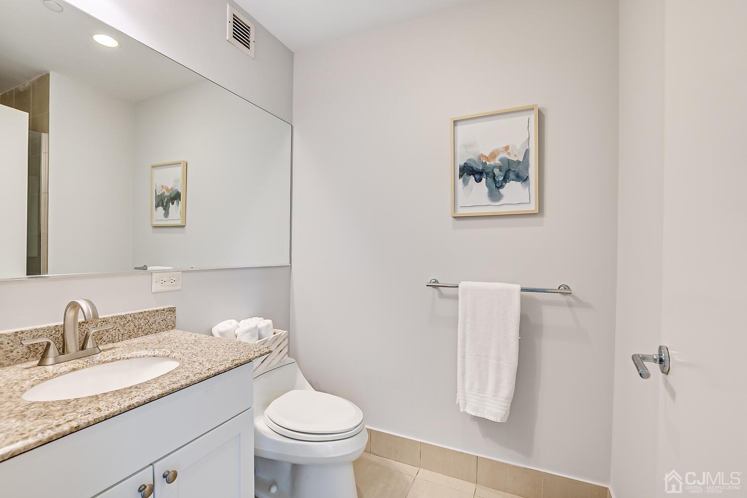 1 Spring Street, Unit 1806 New Brunswick, NJ 08901 - Photo 31 of 57 a bathroom with a granite countertop sink mirror vanity and toilet