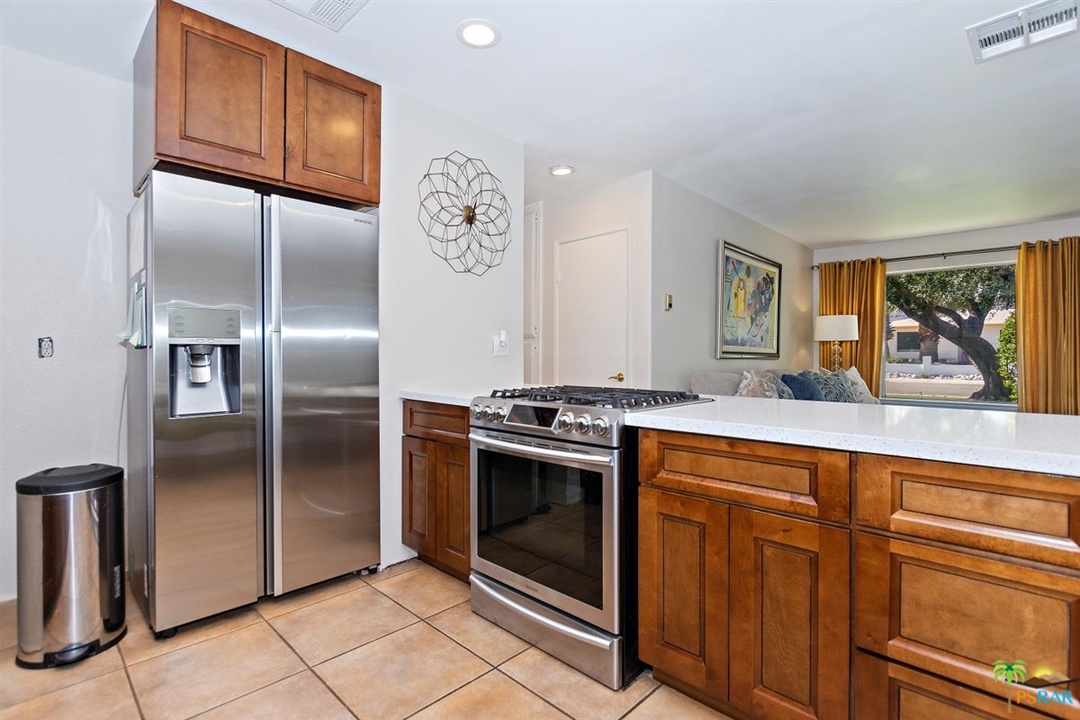 2802 North Chuperosa Road Palm Springs, CA 92262 - Photo 6 of 25 a kitchen with stainless steel appliances granite countertop a refrigerator a sink and wooden cabinets