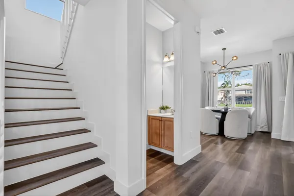 a kitchen with stainless steel appliances granite countertop a refrigerator a sink a stove and white cabinets with wooden floor