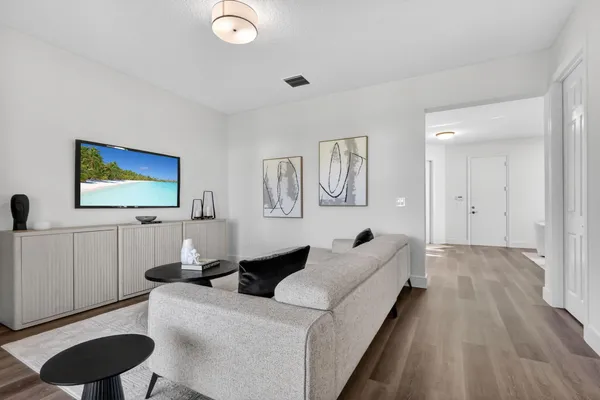a view of a hallway with wooden floor and a bathroom