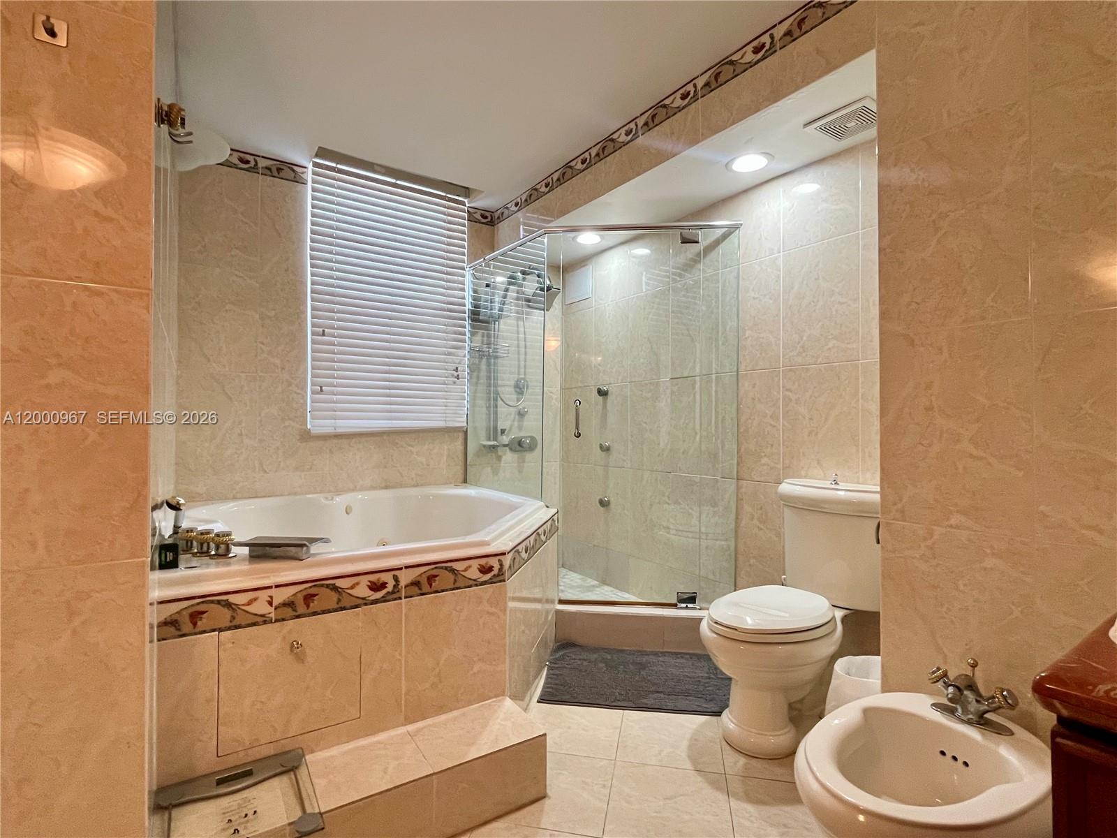 9511 Collins Avenue, Unit 811 Surfside, FL 33154 - Photo 13 of 29 a bathroom with a sink a toilet a mirror and shower