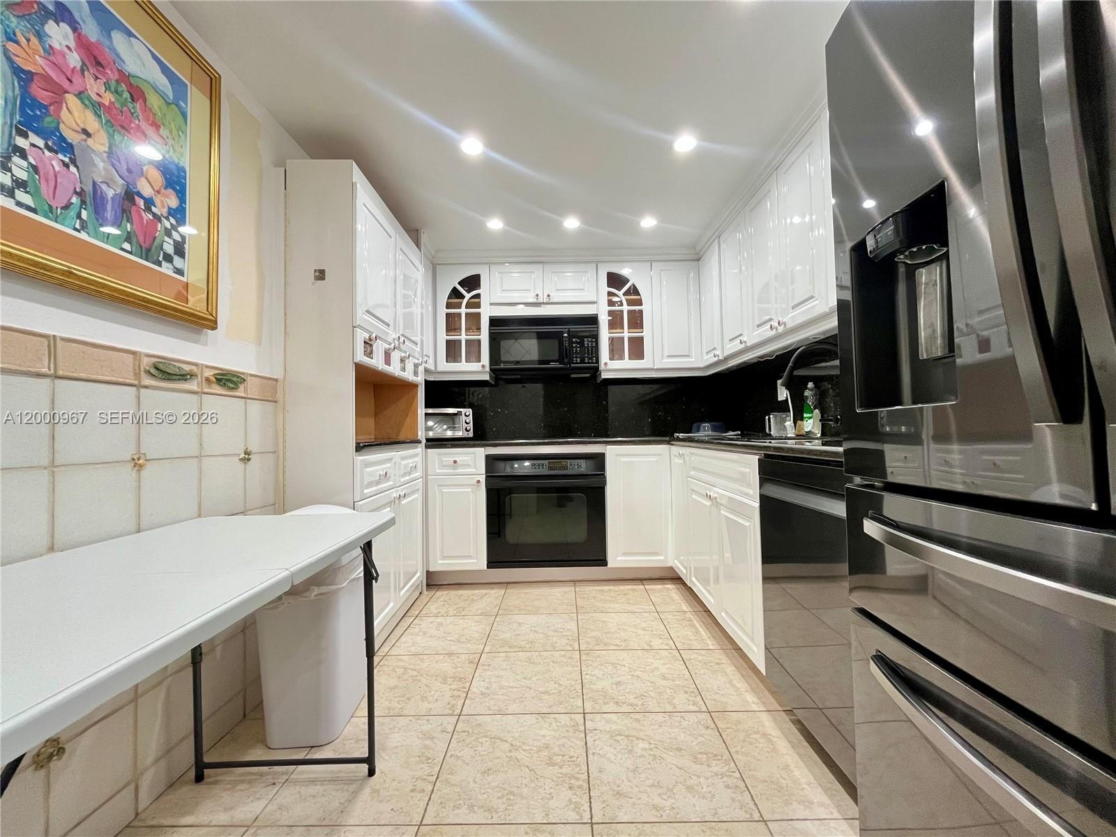 9511 Collins Avenue, Unit 811 Surfside, FL 33154 - Photo 7 of 29 a kitchen with stainless steel appliances kitchen island granite countertop a stove a sink and a microwave