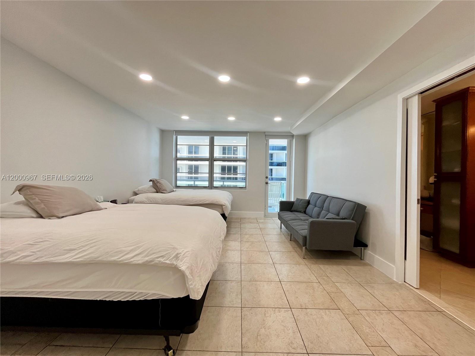 9511 Collins Avenue, Unit 811 Surfside, FL 33154 - Photo 8 of 29 a spacious bedroom with a bed and a couch