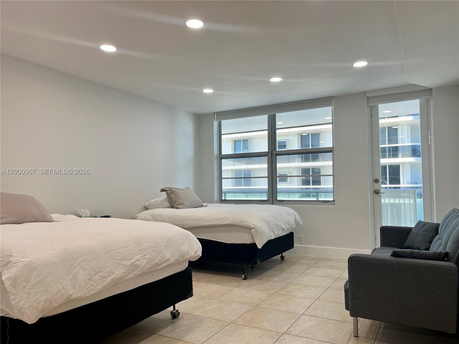 9511 Collins Avenue, Unit 811 Surfside, FL 33154 - Photo 10 of 29 a bedroom with two beds and a couch with window