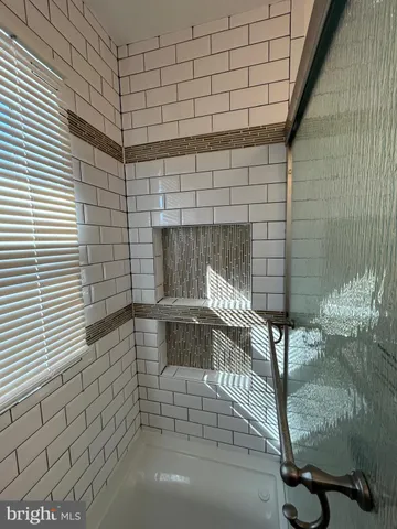 a view of a refrigerator in kitchen and an empty room with wooden floor