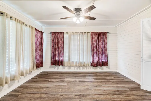 a view of a livingroom with a fireplace a chandelier fan and wooden floor