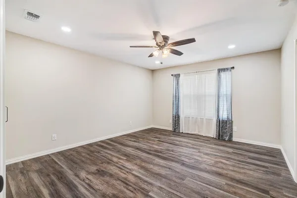 a view of empty room with wooden floor and fan