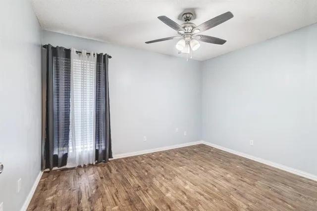 an empty room with windows and fan