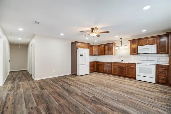 a large kitchen with stainless steel appliances granite countertop a sink and dishwasher a stove with wooden floors