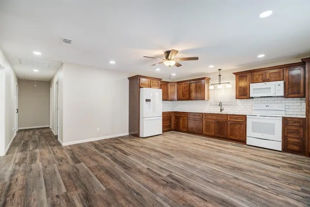 a large kitchen with stainless steel appliances granite countertop a sink and dishwasher a stove with wooden floors