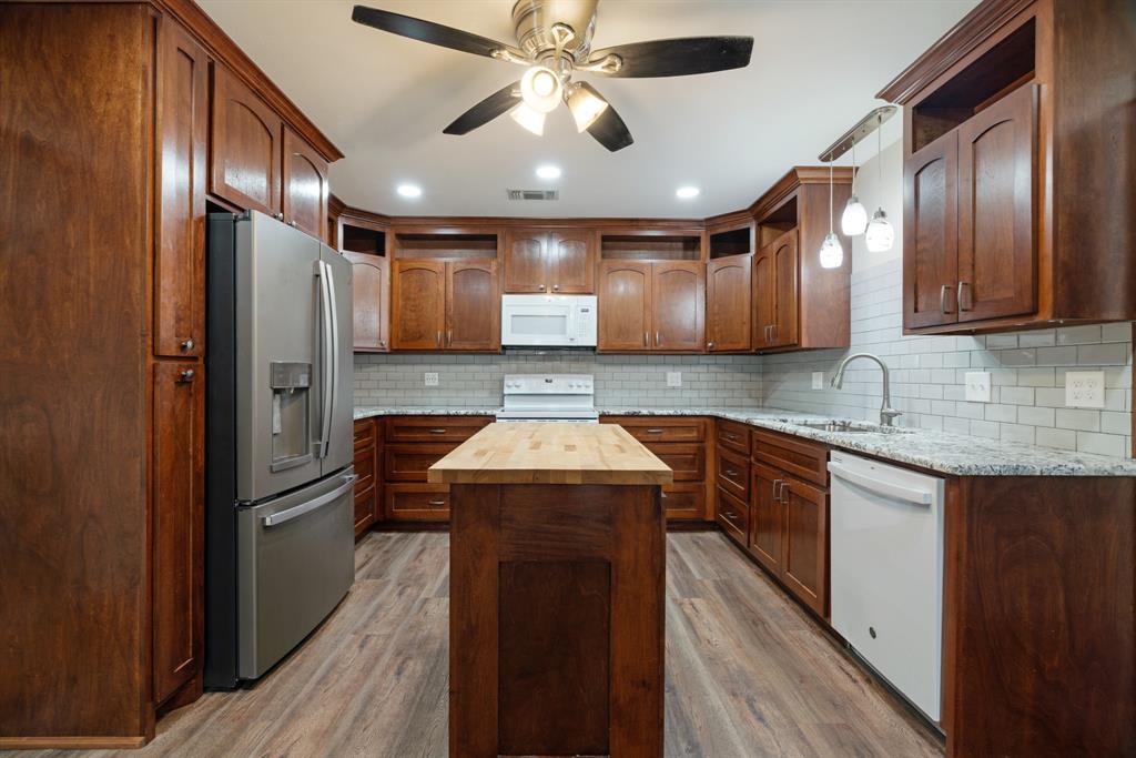 201 Farm To Market 906 Powderly, TX 75473 - Photo 6 of 32 a kitchen with stainless steel appliances granite countertop wooden cabinets a sink and a refrigerator