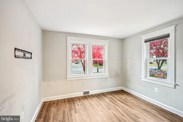 a view of an empty room with window and wooden floor