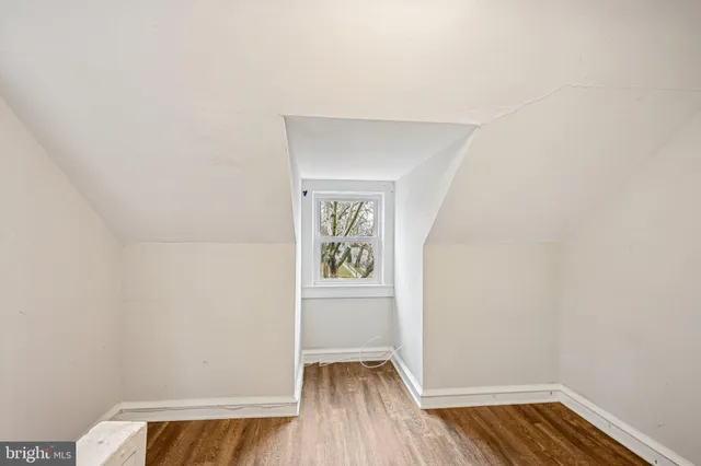 an empty room with wooden floor chandelier fan and windows
