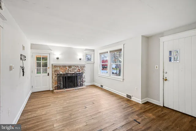 an empty room with windows and fireplace