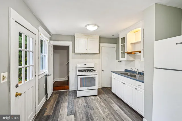 a kitchen with a refrigerator a sink and wooden floor