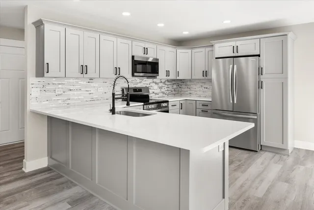 a kitchen with kitchen island a white counter top space cabinets stainless steel appliances and cabinets
