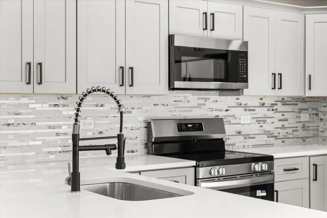 a kitchen with granite countertop a stove microwave and sink