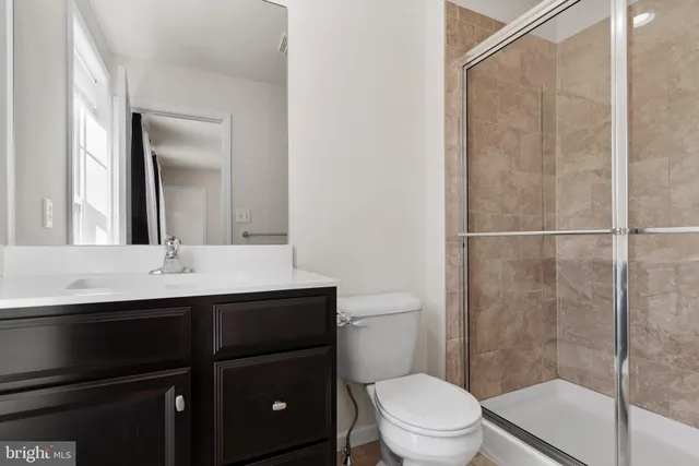 a bathroom with a sink a toilet a mirror and shower