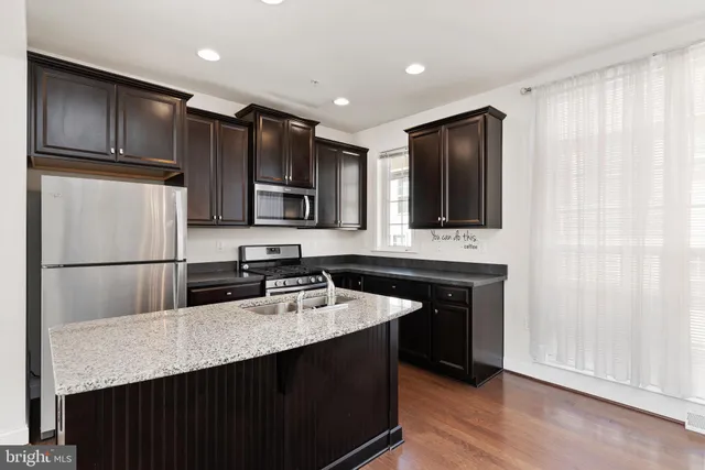 a kitchen with stainless steel appliances granite countertop a refrigerator a sink and wooden cabinets