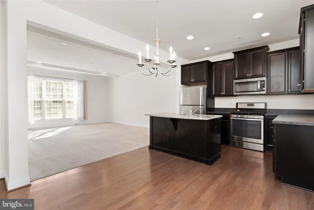 a kitchen with kitchen island granite countertop stainless steel appliances cabinets a sink and a counter top space