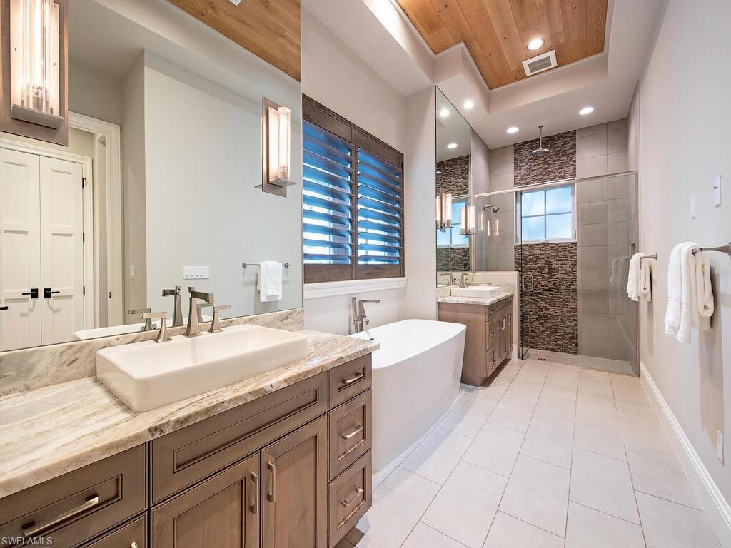9200 Mercato Way Naples, FL 34108 - Photo 12 of 13 a spacious bathroom with a granite countertop sink a bathtub a mirror and vanity