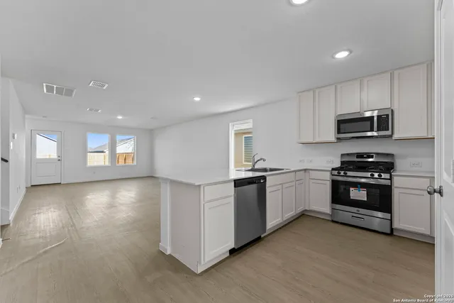a kitchen with granite countertop a refrigerator and a stove top oven