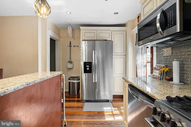 a kitchen with stainless steel appliances granite countertop a refrigerator a stove and a sink with wooden floor