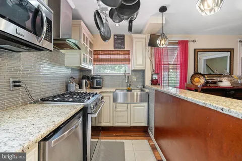 a kitchen with stainless steel appliances granite countertop a sink a stove and a wooden cabinets