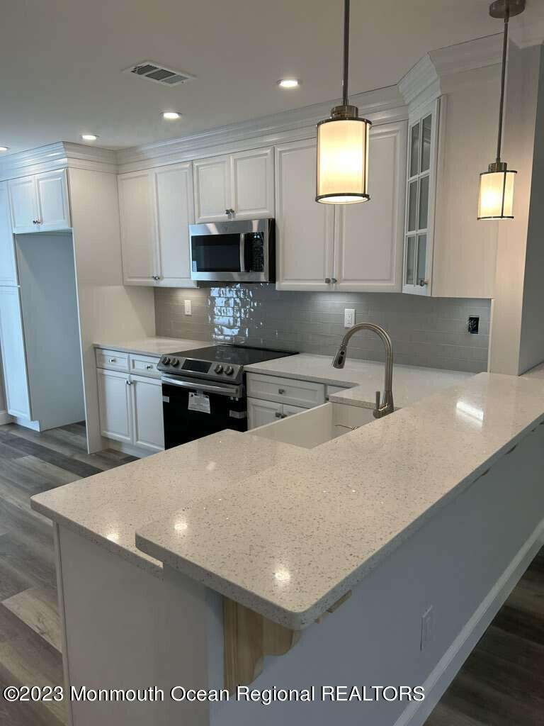 48 East Piazza Tasso Freehold, NJ 07728 - Photo 9 of 21 a kitchen with stainless steel appliances a sink a stove a refrigerator a center island and furniture