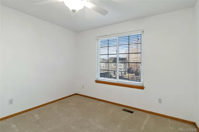 an empty room with a ceiling fan and a window
