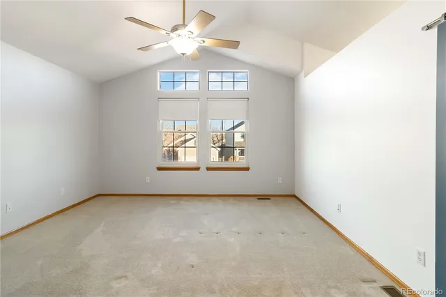 an empty room with chandelier fan and windows
