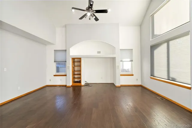 an empty room with wooden floor cabinet and windows