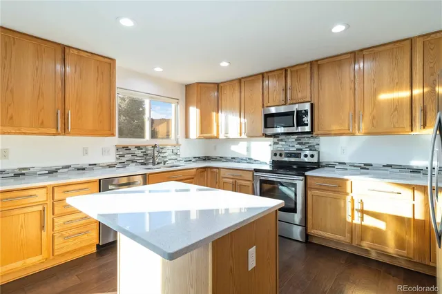 a kitchen with stainless steel appliances granite countertop wooden cabinets a stove top oven a sink and dishwasher